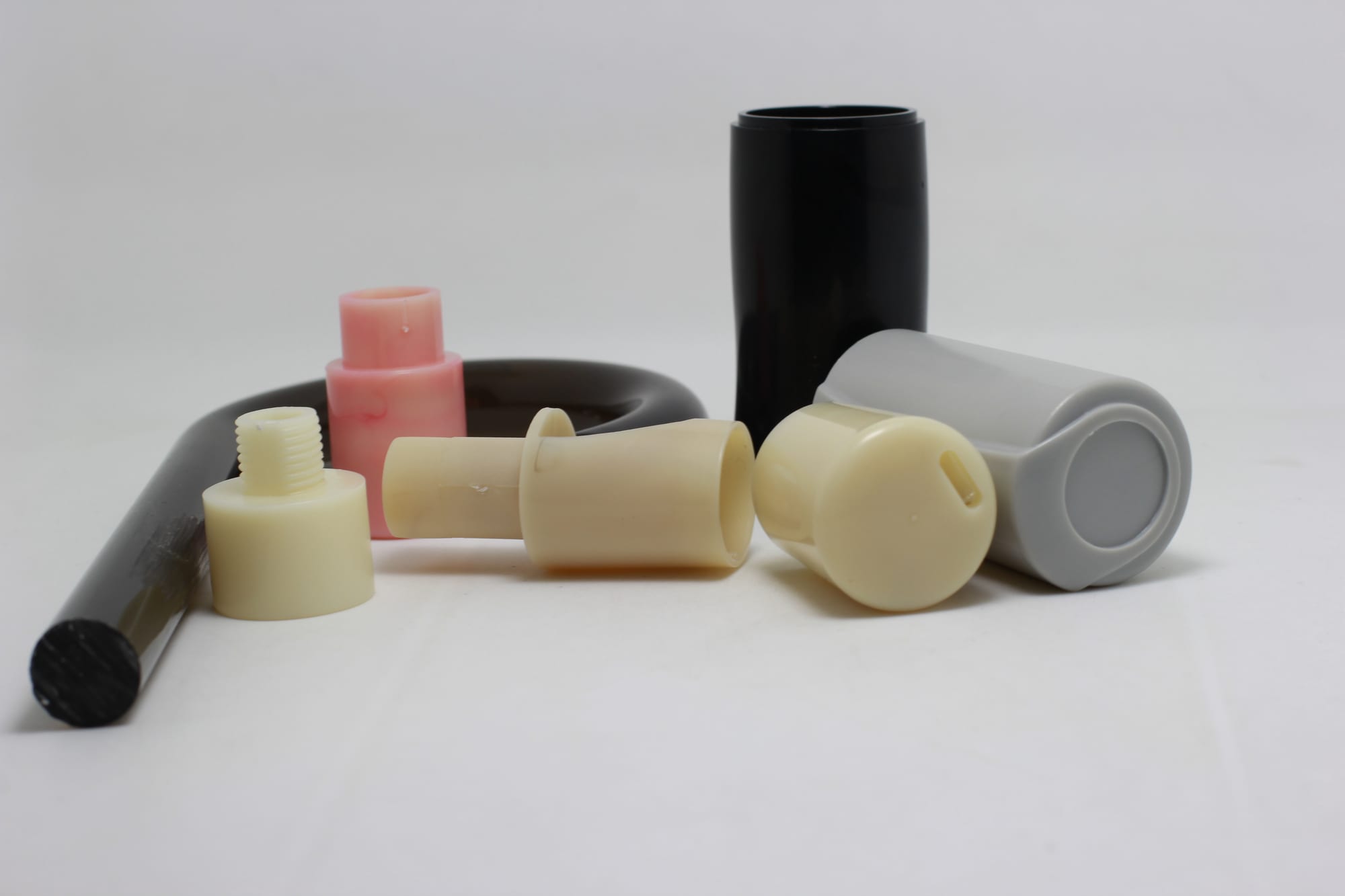 The image shows a white table with a variety of different types of plastic bottles, including a lip balm tube, a lip gloss tube, and a lip liner tube, all of which are part of a wholesale plastic tube
